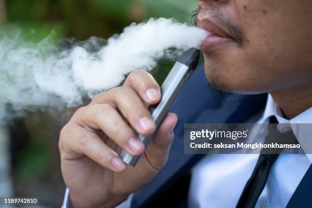 young male worker smoking electronic cigarette - world health organisation calls for regulation of ecigarettes stockfoto's en -beelden