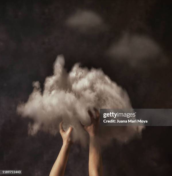 conceptual photography hands grab a big cloud from the sky. suggest the idea of getting dreams - dream big stockfoto's en -beelden