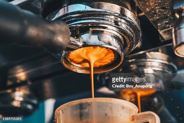 close up of espresso machine making an espresso with a "naked" portafilter, directs high-pressure hot water through the coffee puck. - coffee machine stockfoto's en -beelden