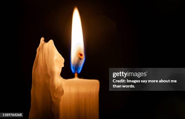 close up of a burning candle against a black background. - candlelight vigil stock pictures, royalty-free photos & images