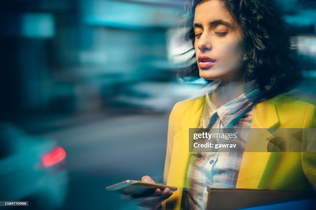 A empresária adulta nova após o uso pesado do smartphone sente tonturas na noite em uma estrada ocupada.
