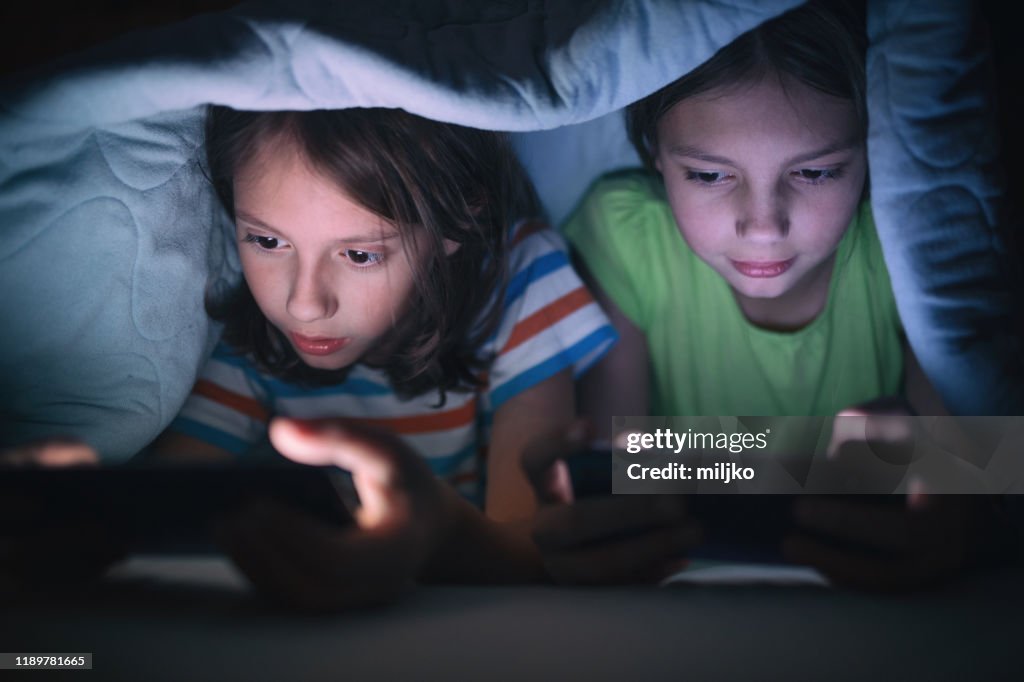 Ragazzo e ragazza che giocano sul cellulare nel loro letto