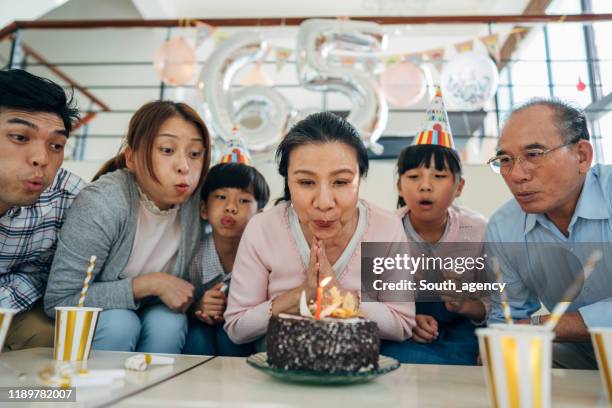 famiglia festeggia compleanno nonne insieme - parents children blow candles asians foto e immagini stock