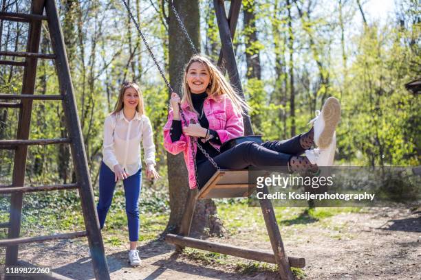 girl swinging her girlfriend - woman on swing stock pictures, royalty-free photos & images