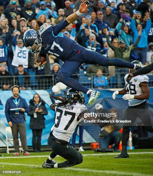 Quarterback Ryan Tannehill of the Tennessee Titans jumps over Tre Herndon of the Jacksonville Jaguars for a touchdown during the first half at Nissan...