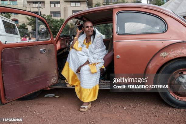 Woman wearing traditional Ethiopian talks in a phone inside a VW Beetle car during the first event gathering owners of classic Volkswagen owners, in...