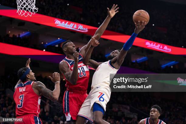 James Ennis III of the Philadelphia 76ers shoots the ball against Bradley Beal and Ian Mahinmi of the Washington Wizards in the second quarter at the...