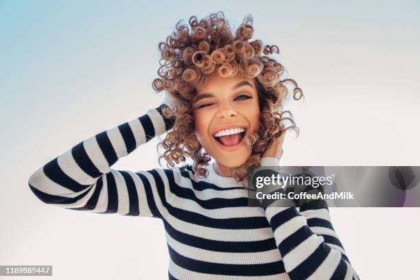 portrait of a happy girl against blue sky - curly hair stock pictures, royalty-free photos & images