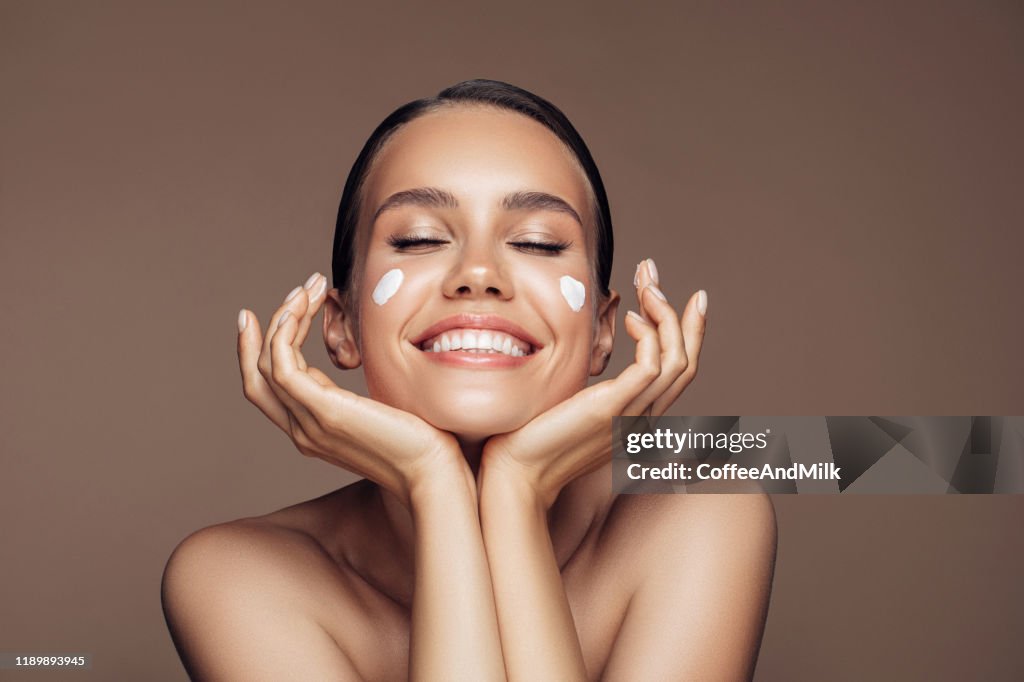Belle femme appliquant la crème sur son visage