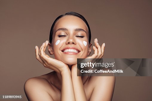 Belle femme appliquant la crème sur son visage Belle femme appliquant la crème sur son visage