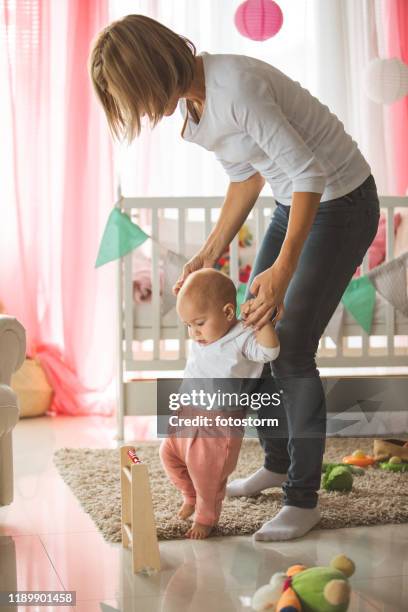 moeder helpen baby dochter lopen in de slaapkamer - first occurrence stockfoto's en -beelden