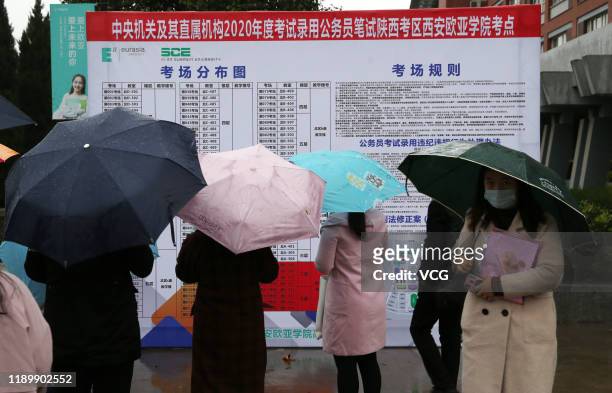 Examinees check information in the rain at an exam site of the national civil servant exam on November 24, 2019 in Xi'an, Shaanxi Province of China....