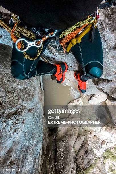 point of view from a brave canyoneer sitting on the canyon drop edge - canyoneering stock pictures, royalty-free photos & images