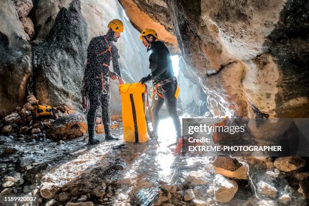 deux canyoneers emballant vers le haut de leur corde statique dans un sac jaune imperméable à l'eau au fond de canyon - résistant �à l'eau photos et images de collection