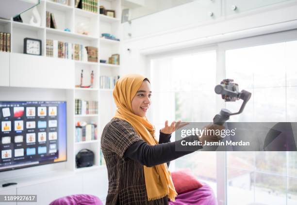 arab girl demonstrating hijab fashion online using steady cam with smartphone - hijab fashion stockfoto's en -beelden