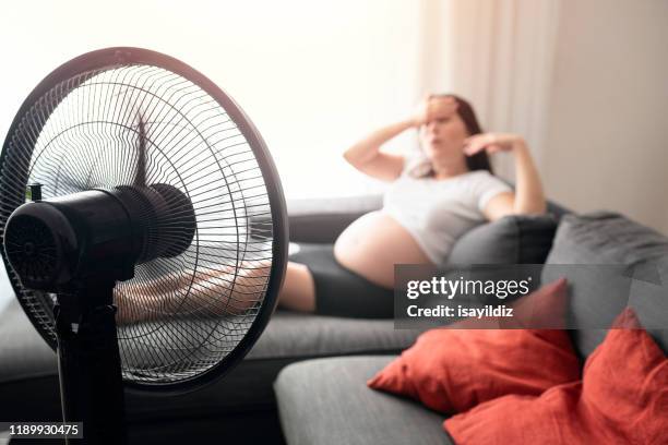 femme enceinte se sentant mal pour la chaleur d'été - ventilateur électrique photos et images de collection