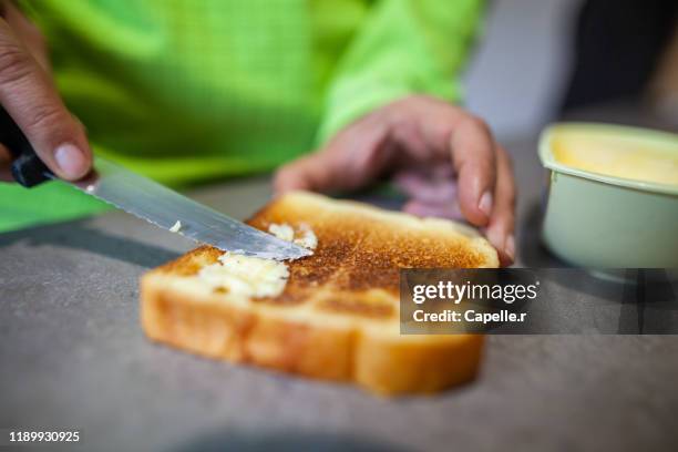 cusine - beurrer une tranche de pain de mie grillé - untar de mantequilla fotografías e imágenes de stock