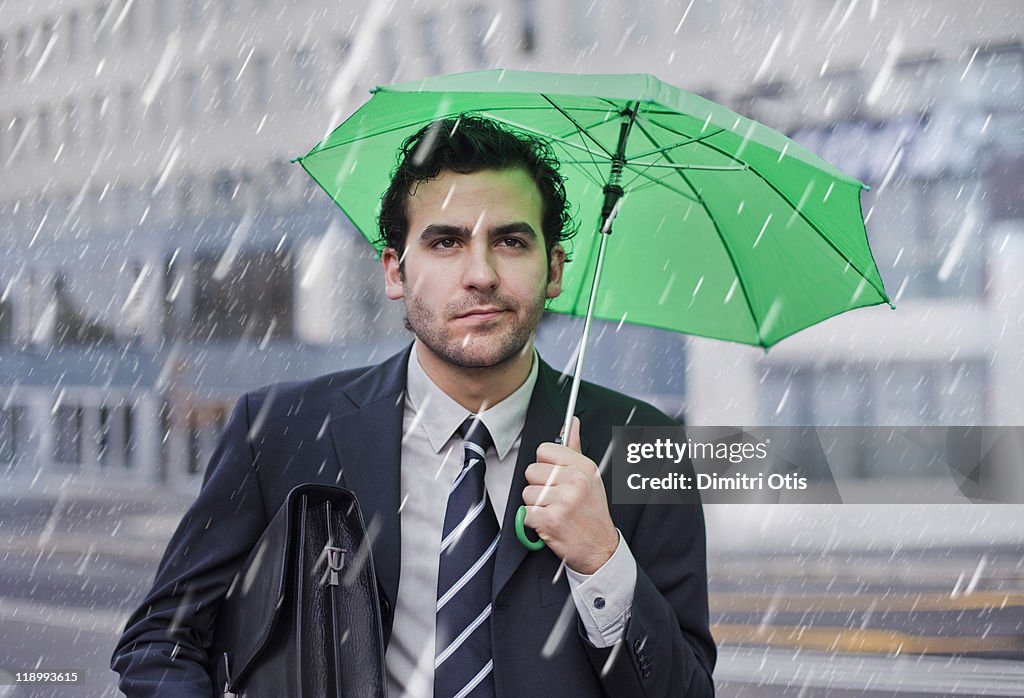 Businessman in the rain with small umbrella