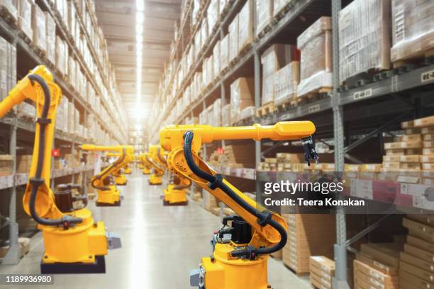 automatic robot mechanical arm is working in temporary storage - robot stock pictures, royalty-free photos & images