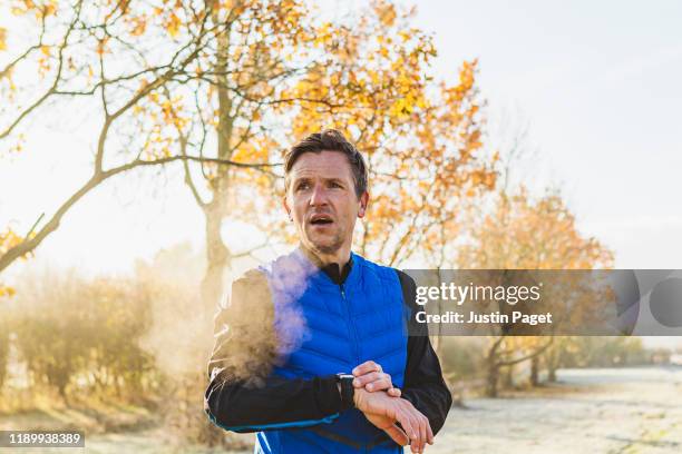 runner using smart watch - frost stock photos et images de collection