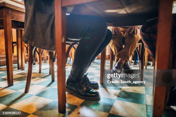 los pies de la gente debajo de la mesa en el café - debajo de fotografías e imágenes de stock