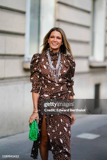 Helena Bordon wears a brown lustrous dress with printed features including polka dots, a bejeweled necklace, a green bag, outside Alessandra Rich,...