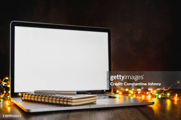 laptop and notebook against christmas lights background - blank laptop screen stock-fotos und bilder