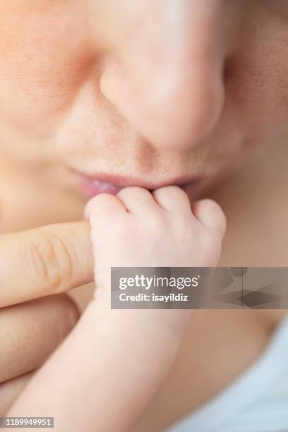 liefdevolle moeder kus haar baby's hand - chest kissing stockfoto's en -beelden