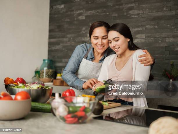 madre latina amorosa enseñando a su hija a cocinar en casa - mature latin women fotografías e imágenes de stock