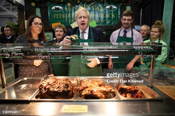 Britain's Prime Minister and Conservative Party leader Boris Johnson greets customers on a stall selling meat sandwiches while visiting the Royal...