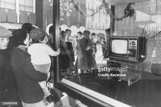 Tokyoites view a Yen 59,800 colour television set through the window of an electrical goods shop after protests led to reduction in the prices of the...