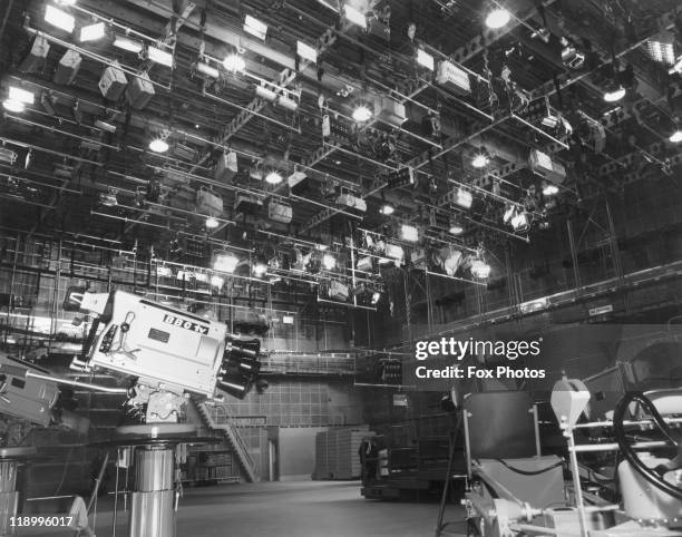 Lighting rigs line the celiling with a BBC TV camera in the foreground in the television studio from which the first programme was transmitted from...