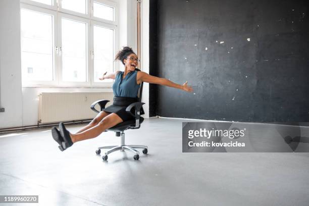 african businesswoman taking a break in the office and rolling on the office chair - friday stock pictures, royalty-free photos & images
