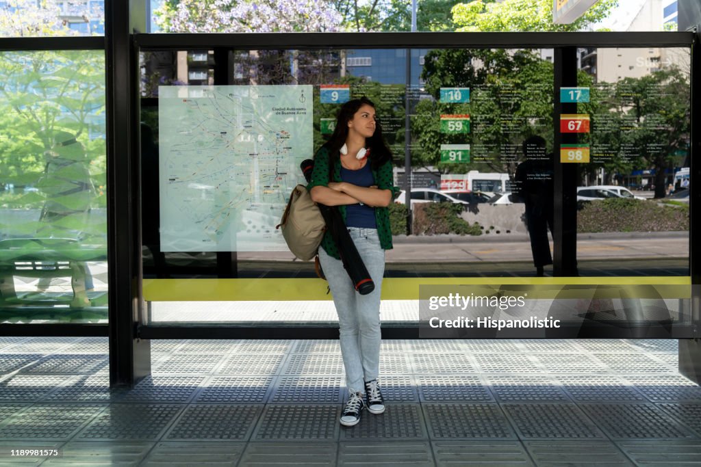 Estudiante latinoamericano en la parada de autobús esperando - Estilos de vida de la ciudad