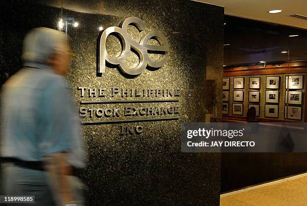 Trader walks in front of the logo of the Philippine Stock Exchange in Manila on July 14, 2011. The PSC said it would extend trading hours, the latest...