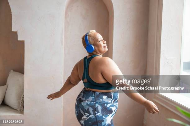 older black woman dancing with headphones on - curvy black women stock-fotos und bilder
