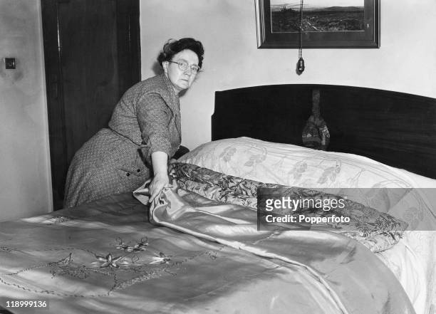 Housekeeper Louisa Merrifield makes the bed in the Blackpool bungalow in which her employer, Sarah Ann Ricketts, was found poisoned, July 1953....