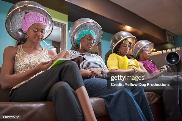 women friends sitting under hair dryers at salon - hairdressers black woman stock pictures, royalty-free photos & images