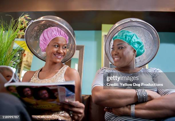 smiling women sitting under hair dryers in salon - blow drying hair stock pictures, royalty-free photos & images