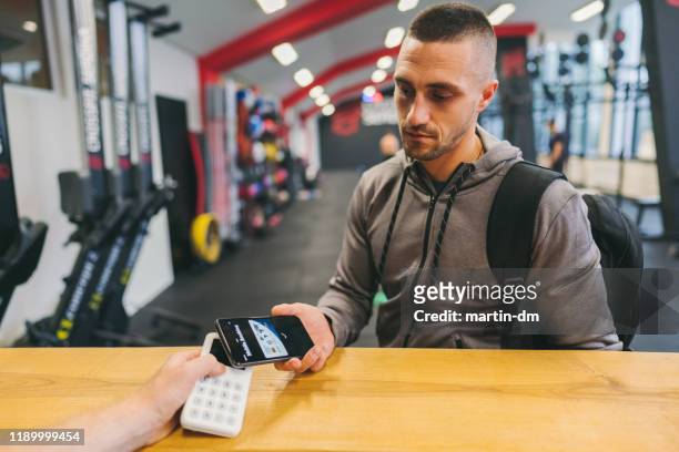 mann im fitnessstudio bezahlt mit digitaler brieftasche - charging sports stock-fotos und bilder