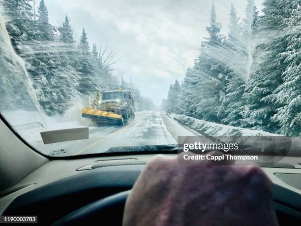 man driving car during winter in rangeley, maine with snowplow coming down road - winter car window stock-fotos und bilder