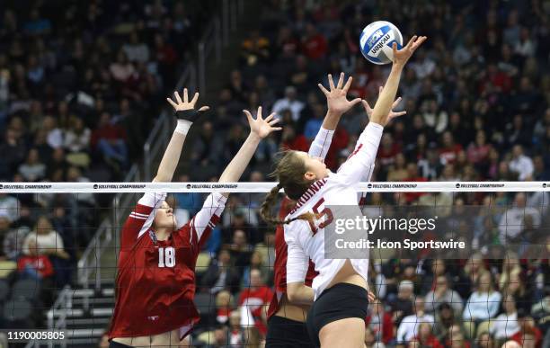 Kathryn Plummer of the Stanford Cardinal tips the ball over the net while a dual block is made by two members of the Wisconsin Badgers during the...