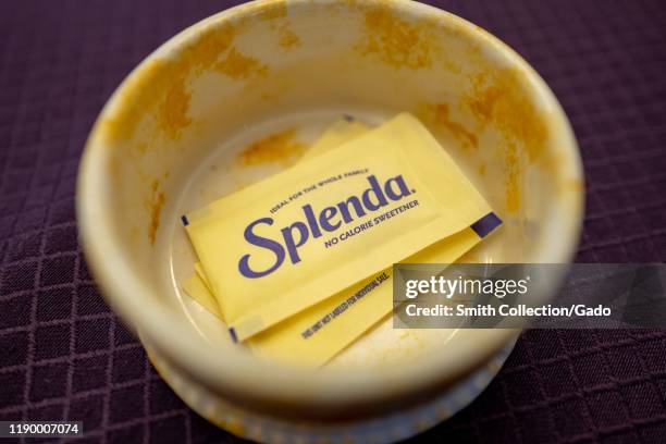 Close-up of packets of Splenda sucralose based artificial sweetener, yellow color, in a yellow ceramic dish, a brand of Heartland Food Products...