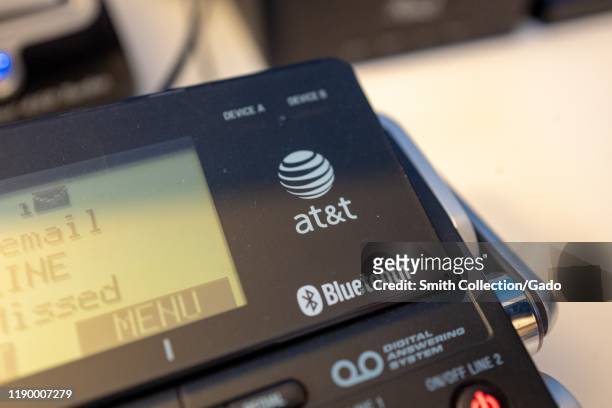 Close-up of logo for telecommunications company ATT on a desktop phone in an office, with Bluetooth logo also visible, August 21, 2019.
