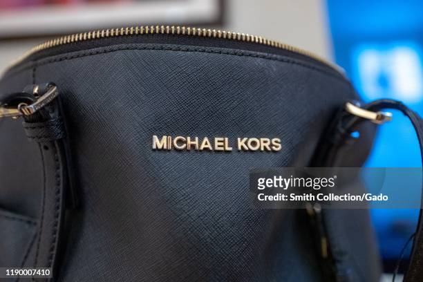 Close-up of logo for apparel company Michael Kors on a black leather handbag in a domestic room, August 21, 2019.