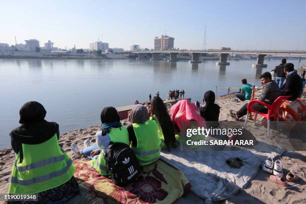 Iraqis wind down on the bank of the Tigris river in the capital Baghdad, on december 21, 2019. - In the heart of Baghdad, a few steps from the famed...