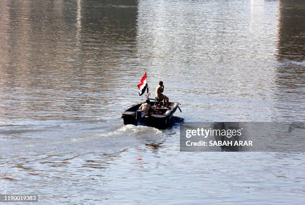 Members of the Iraqi military steer a boat in the waters of the Tigris river in the capital Baghdad, on december 21, 2019. - In the heart of Baghdad,...