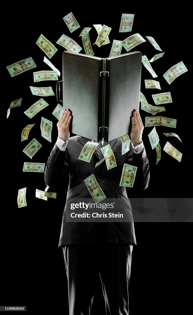 Business man holding a briefcase with money flying