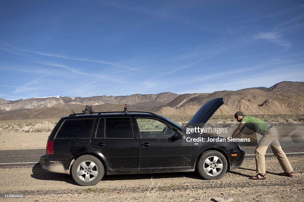 Man standing near a broke down car.