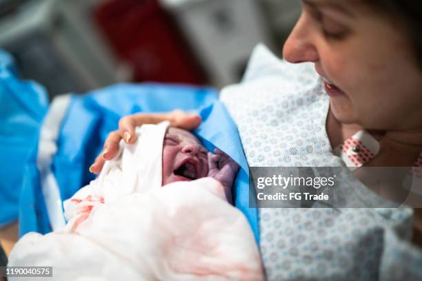 lächelnde mutter hält ihr baby im krankenhaus - kaiserschnitt stock-fotos und bilder